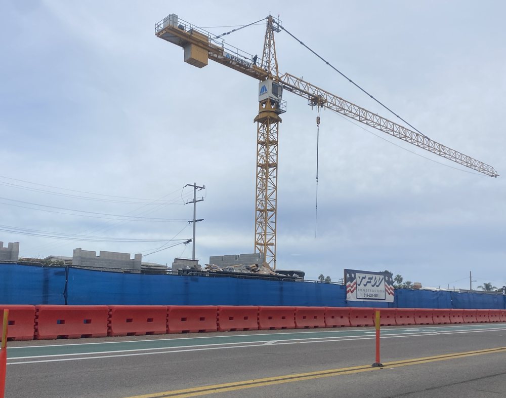 A tower crane over the construction site on Coast Highway 101 in Leucadia where Captain Keno's and the Portofino Beach Hotel stood, behind blue fencing and orange barriers