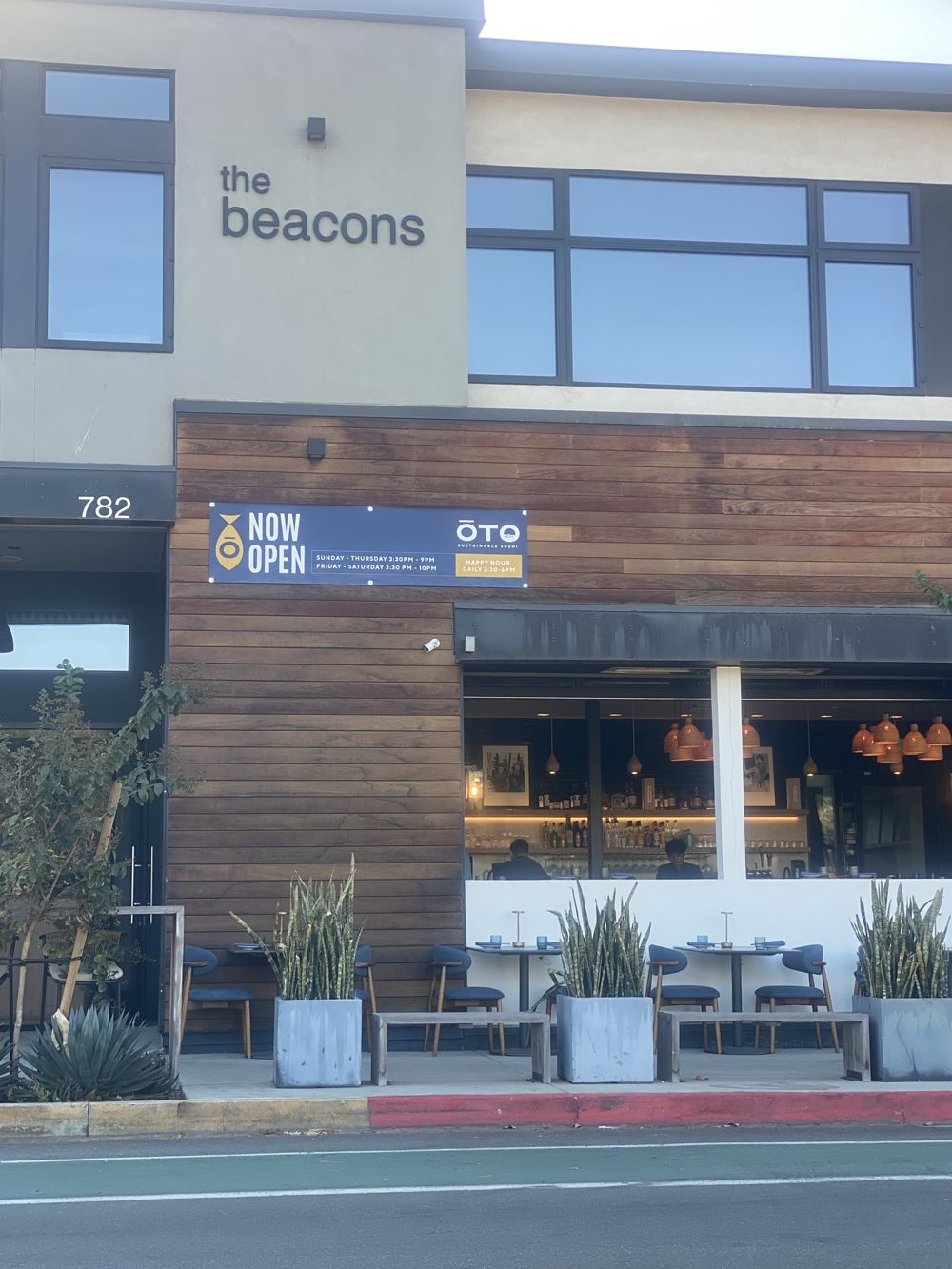 ŌTO Sustainable Sushi's NOW OPEN banner on The Beacons building on Coast Highway 101 in Leucadia, with its open-air bar and patio
